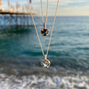 Heart shaped aquamarine with handcrafted bezel on dainty chain, ocean in the background 