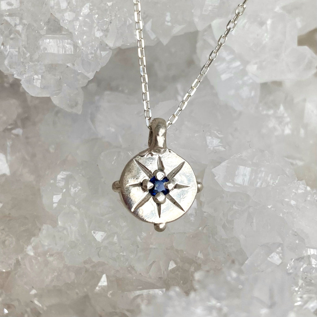 Silver coin pendant with engraved star and blue sapphire 